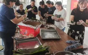 戴着一次性手套和食品专用口罩的同事正在包粽子